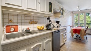 Una cocina con muebles blancos, lavavajillas y comedor con mesa dispuesta para dos.