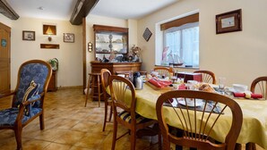 A dining area with a wooden table set for breakfast, surrounded by chairs, and a window with a view of the outside.