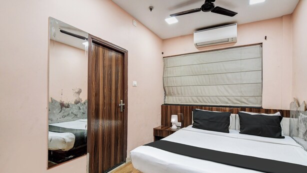 Quarto com cama, mesa de cabeceira, espelho, ventilador de teto e ar-condicionado.