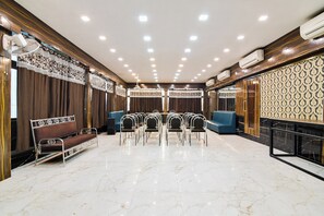 A hotel lobby with a marble floor, rows of chairs, a sofa, and a patterned wall.