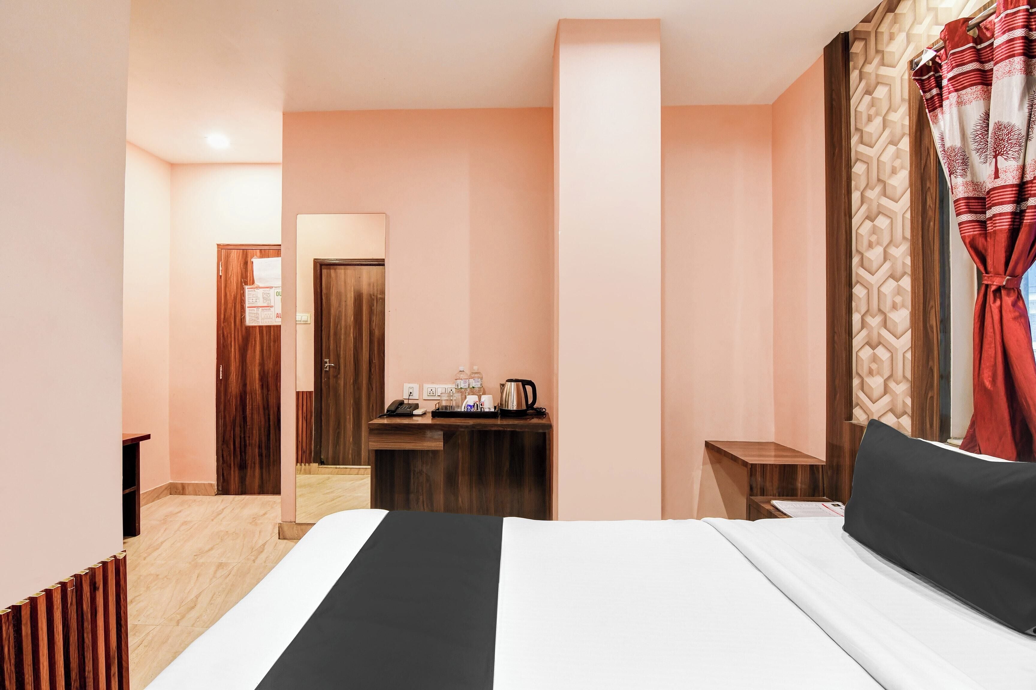 Habitación de hotel con cama, escritorio con teléfono y cafetera, y una puerta que da a otra habitación.