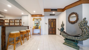Vestíbulo de hotel con mostrador de recepción, taburetes de bar, una estatua decorativa y una puerta tradicional.