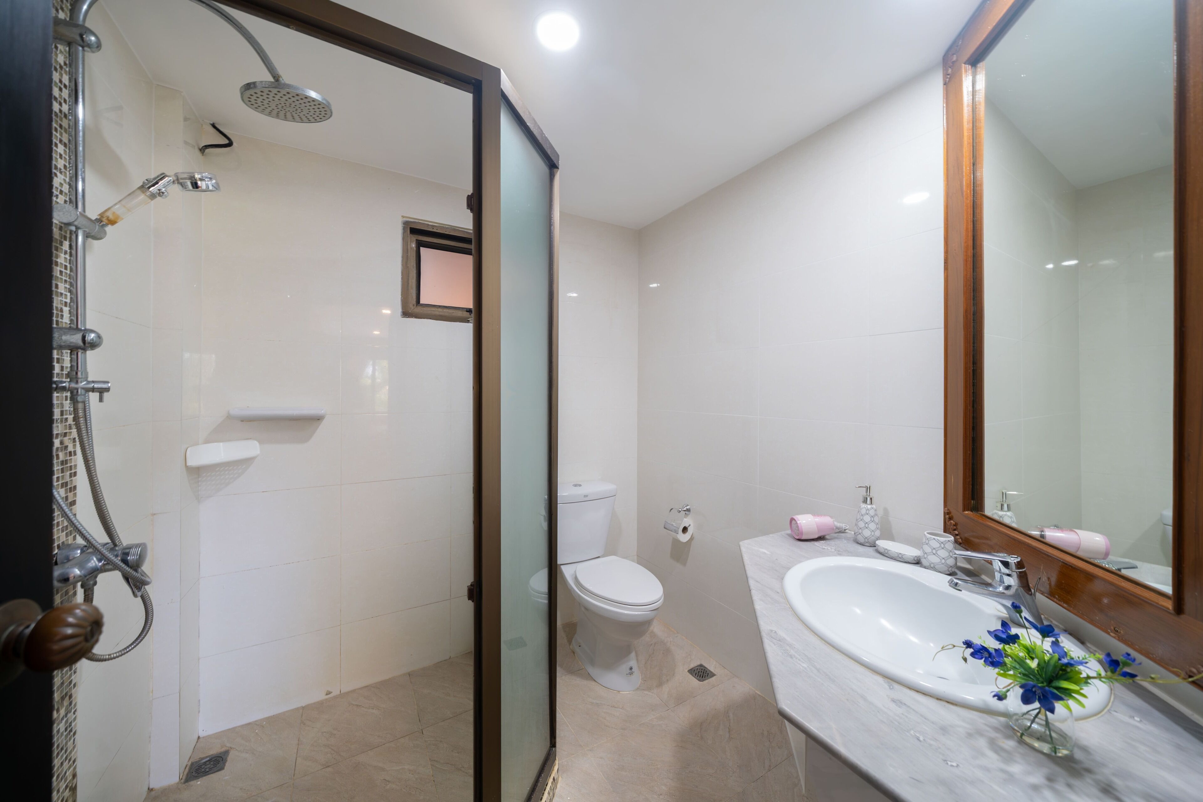A bathroom with a shower, toilet, sink, and a mirror.