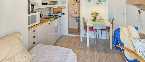 A compact living space with a kitchenette, a dining area, and a bed.