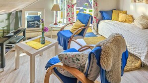 A cozy room with a bed, a chair, a table with a vase, and a television.