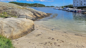 A coastal area with clear water, rocky shores, and boats docked near a building.