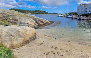 A coastal area with clear water, rocky shores, and boats docked near a building.