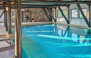An indoor swimming pool with clear blue water, stone walls, and a view of the outdoors. - Stunning home in Tjørhom with sauna (Tjørhom)