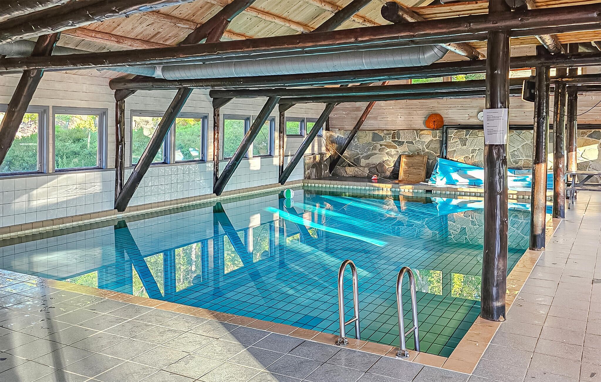 An indoor swimming pool with clear water, surrounded by stone walls and wooden beams.