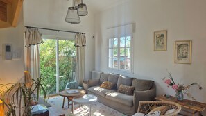 Ein gemütliches Wohnzimmer mit einer Couch, einem runden Tisch und einem Fenster mit Vorhängen.