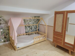 Ein Zimmer mit einem Holzbett, einem Kleiderschrank mit Spiegel und einer Wand mit einem tropischen Wandbild.
