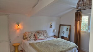 Ein Schlafzimmer mit einem Bett, Nachttischlampen, einem Spiegel und einem Fenster mit Vorhängen.