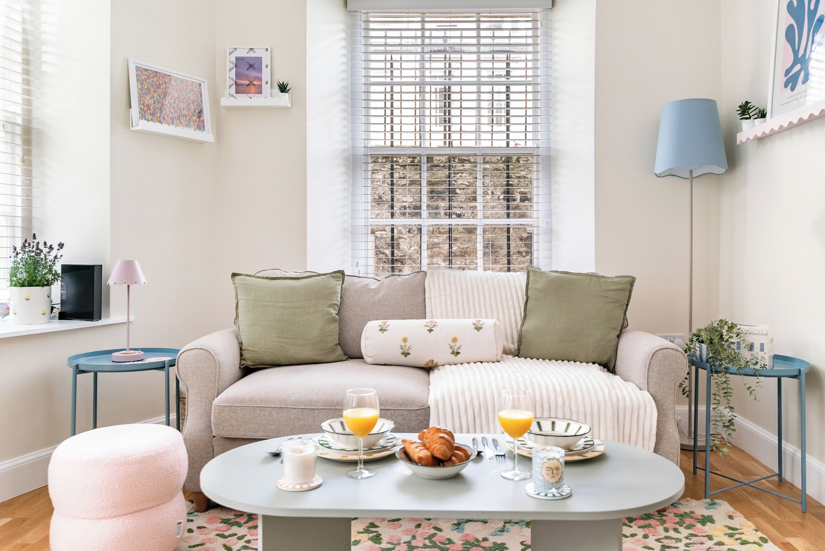 A cozy living room with a sofa, a coffee table, and a dining table set for breakfast.