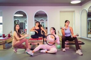 Um estúdio de ginástica com equipamentos de exercício, espelhos e um aparelho de Pilates.