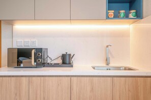 Une cuisine moderne équipée d’un grille-pain encastré, d’une bouilloire et d’un évier.