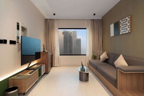 A modern living room with a sofa, a TV, a coffee table, and a window with a city view. - The Longevity Retreat | Luxury Wellness Stay (Jumeirah Village Triangle)
