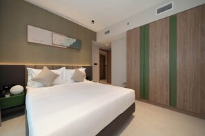 A modern hotel room with a large bed, a nightstand, a wall-mounted artwork, and a wardrobe with vertical wood panels. - The Longevity Retreat | Luxury Wellness Stay (Jumeirah Village Triangle)
