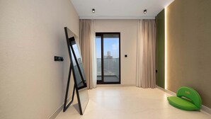 Ein modernes Zimmer mit einer großen Schiebeglaswand, einer Projektionsleinwand und einem grünen Sessel.