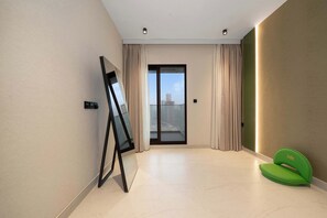 Ein modernes Zimmer mit einer großen Schiebeglaswand, einer Projektionsleinwand und einem grünen Sessel.