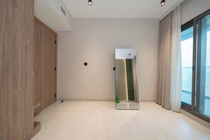 A modern hotel room with a large mirror, a wooden wardrobe, and a view through a large window. - The Longevity Retreat | Luxury Wellness Stay (Jumeirah Village Triangle)