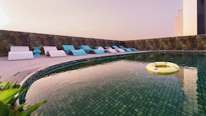 A rooftop pool area with lounge chairs and a floating ring. - Deluxe Escape  Luxury Wellness Hotel (Jumeirah Village Triangle)