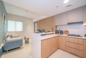 A modern kitchen with a central island, wooden cabinets, and a built-in microwave. - Deluxe Escape  Luxury Wellness Hotel (Jumeirah Village Triangle)