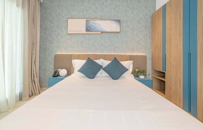Une chambre d’hôtel comprenant un lit, une table de chevet avec un téléphone et une lampe, une œuvre d’art accrochée au mur et une armoire.