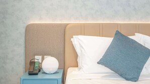 A hotel room with a bed, pillows, a nightstand with a lamp, and a telephone. - Deluxe Escape  Luxury Wellness Hotel (Jumeirah Village Triangle)