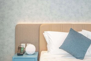 A hotel room with a bed, pillows, a nightstand with a lamp, and a telephone. - Deluxe Escape  Luxury Wellness Hotel (Jumeirah Village Triangle)