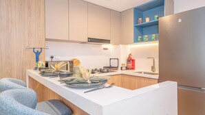 A modern kitchen with a central island, built-in appliances, and a blue upper shelf. - Deluxe Escape  Luxury Wellness Hotel (Jumeirah Village Triangle)