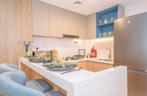 A modern kitchen with a central island, built-in appliances, and a blue upper shelf. - Deluxe Escape  Luxury Wellness Hotel (Jumeirah Village Triangle)