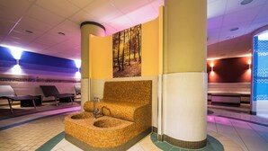 Uma área de spa com uma banheira circular e trançada, um banco de madeira e um quadro na parede com uma floresta.