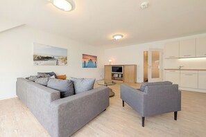 A modern living room with a grey sofa, a glass coffee table, and a flat-screen TV. - Seestern Residence, Apartment 32 (Ostseebad Boltenhagen)