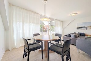 Ein modernes Wohnzimmer mit einem runden Tisch, vier Stühlen, einem grauen Sofa und einem Bild an der Wand.