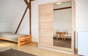 Eine kleine Einzimmerwohnung mit Bett, Schiebetür, Stuhl, Tisch und Kühlschrank.