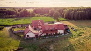 A large, two-story building with a red roof, surrounded by lush green fields and trees. - Nice apartment in Przechlewo with sauna (Przechlewo)