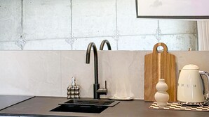 A kitchen with a modern faucet, a wooden cutting board, and a vintage-style coffee maker on the counter. - Amazing apartment in Miedzybrodzie Zywiec (Miedzybrodzie Zywiec)