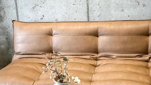A tan leather sofa with a white vase containing flowers. - Amazing apartment in Miedzybrodzie Zywiec (Miedzybrodzie Zywiec)