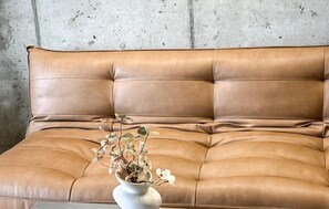 A tan leather sofa with a white vase containing flowers. - Amazing apartment in Miedzybrodzie Zywiec (Miedzybrodzie Zywiec)