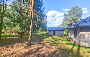 Eine rustikale Holzhütte mit blauem Dach, umgeben von Bäumen und einer Wiese.