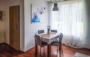 Ein Essbereich mit einem Tisch für vier Personen, einer Blumenvase und einem Gemälde an der Wand.