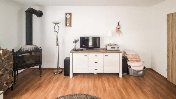 Ein Wohnzimmer mit Fernseher, einer Uhr, einer Lampe und einem Kamin.