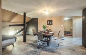 A dining area with a table set for four, surrounded by wicker chairs, a chandelier, and a painting on the wall. - Stunning apartment in Grzybowo (Grzybowo)