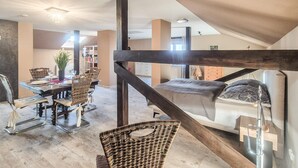 Amplio dormitorio tipo loft con una cama grande, una viga de techo de madera y vistas al área de estar.