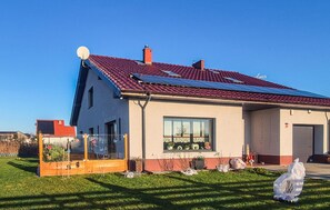 A modern house with a red-tiled roof, solar panels, and a well-maintained lawn. - Stunning apartment in Grzybowo (Grzybowo)