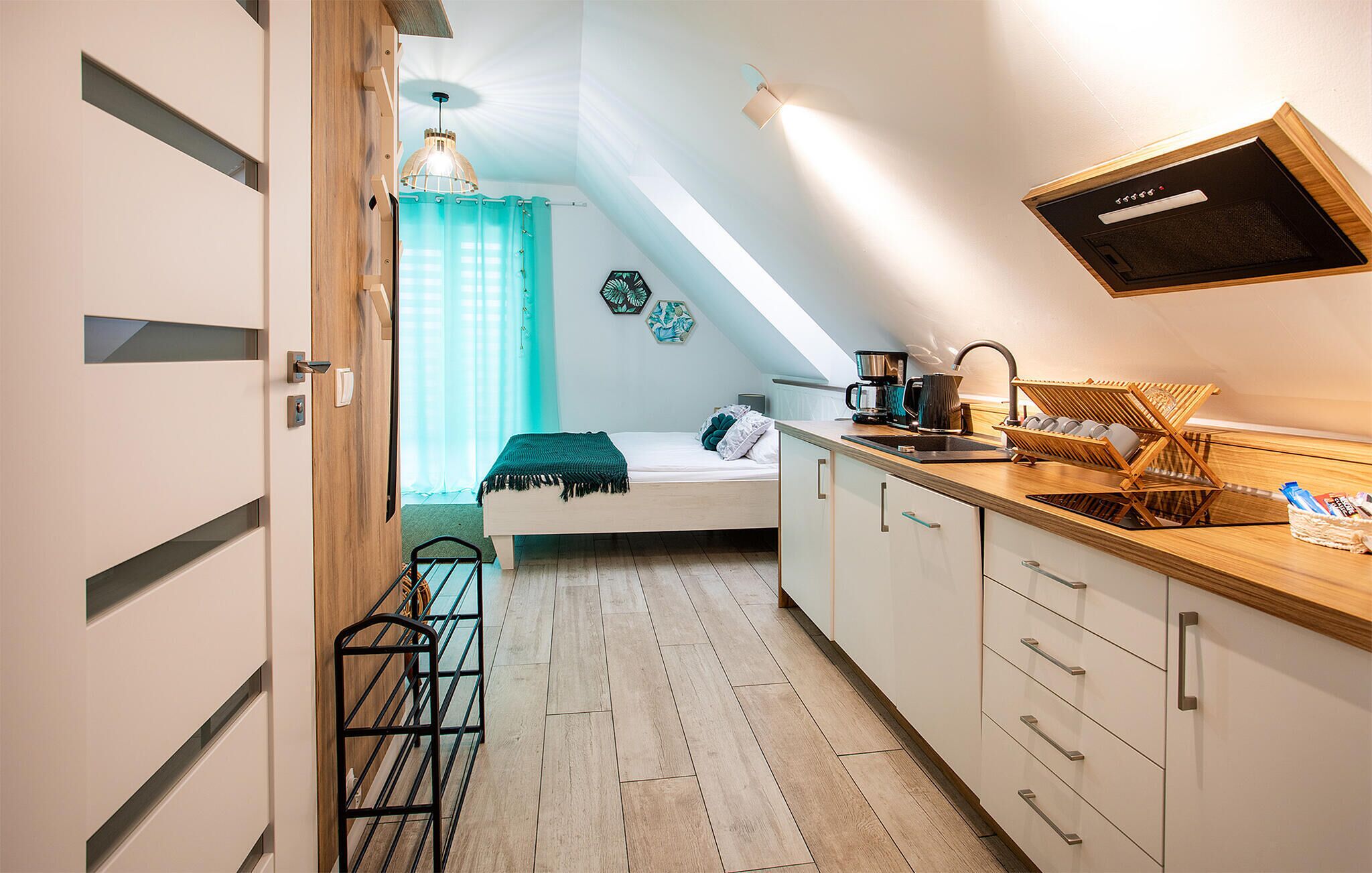 Habitación compacta y moderna con cama, kitchenette y tragaluz.