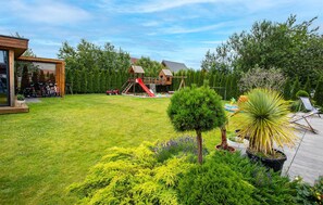 A backyard with a wooden deck, a play area with a slide, and various potted plants. - Gorgeous apartment in Nowecin with WiFi (Nowecin)