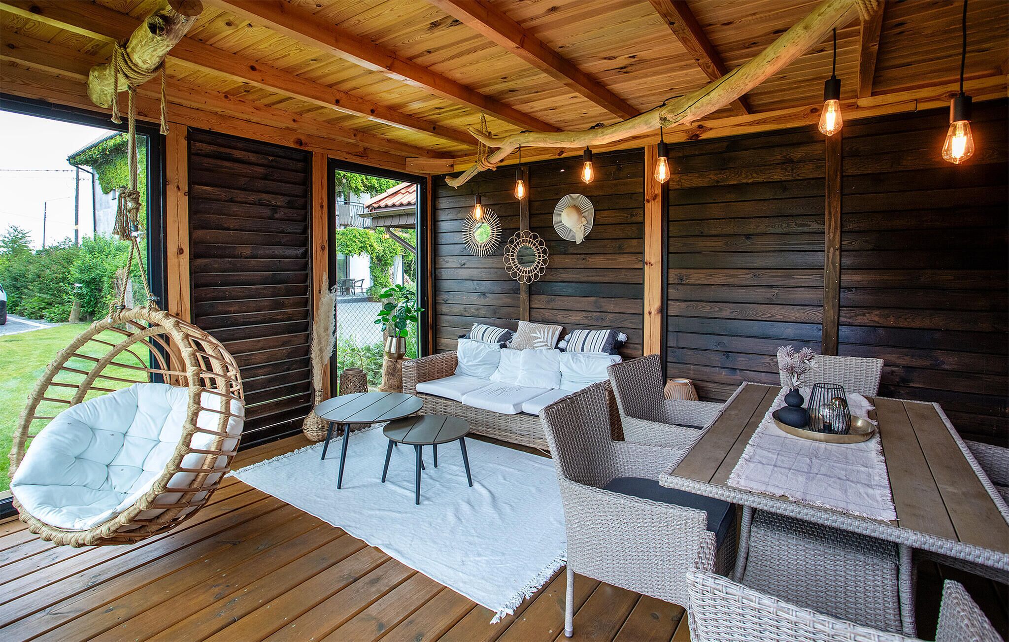A wooden deck with wicker furniture, including a hanging chair and a sofa set.