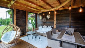 A wooden deck with wicker furniture, including a hanging chair and a sofa set. - Gorgeous apartment in Nowecin with WiFi (Nowecin)
