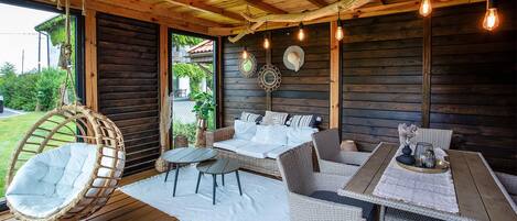 A wooden deck with wicker furniture, including a hanging chair and a sofa set.